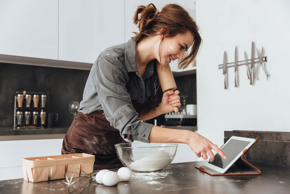 Woman cooking while looking at tablet