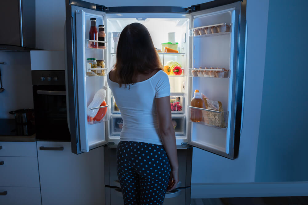 Woman looking in fridge at night